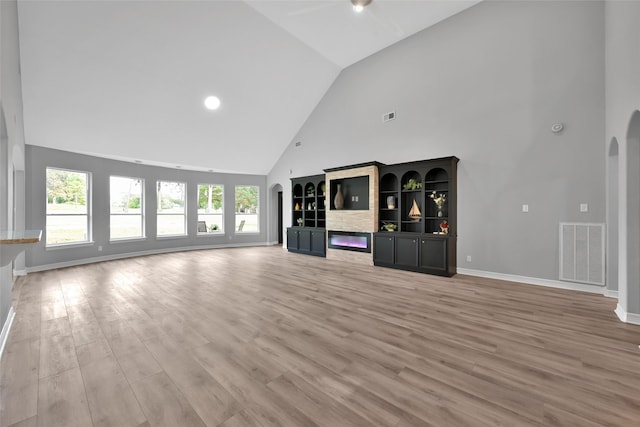 13646 Leafy Arbor Dr, Montgomery, TX 77356 - unfurnished living room featuring high vaulted ceiling, light wood-type flooring, arched walkways, ceiling fan, and baseboards