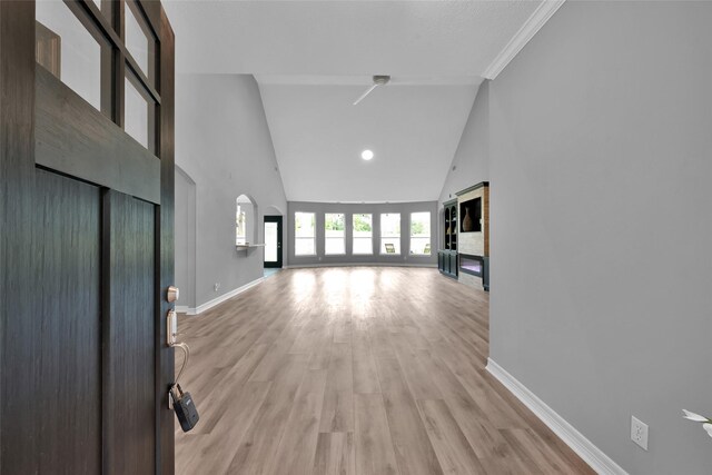 13646 Leafy Arbor Dr, Montgomery, TX 77356 - unfurnished living room featuring high vaulted ceiling, baseboards, light wood finished floors, arched walkways, and recessed lighting
