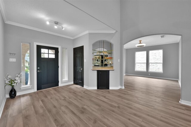 13646 Leafy Arbor Dr, Montgomery, TX 77356 - foyer featuring light wood-style flooring, ornamental molding, bar, baseboards, and arched walkways