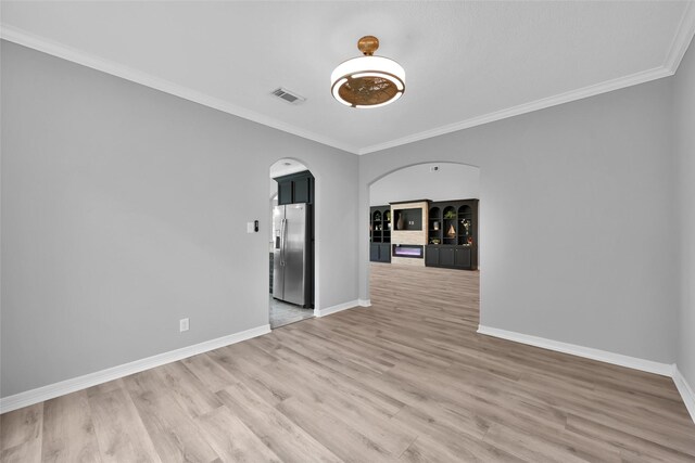13646 Leafy Arbor Dr, Montgomery, TX 77356 - empty room with arched walkways, crown molding, baseboards, and light wood-style floors