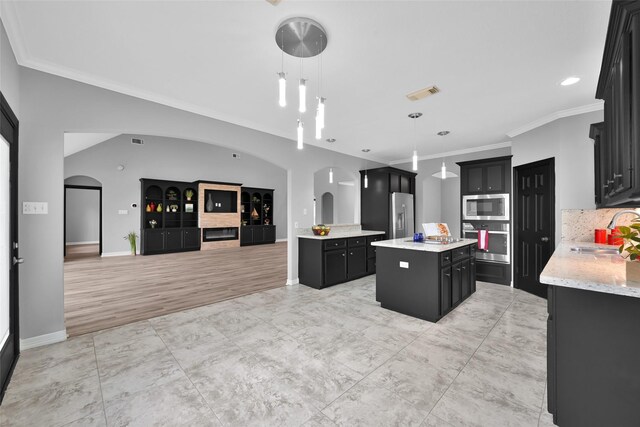 13646 Leafy Arbor Dr, Montgomery, TX 77356 - kitchen featuring stainless steel appliances, dark cabinetry, open floor plan, arched walkways, and a sink