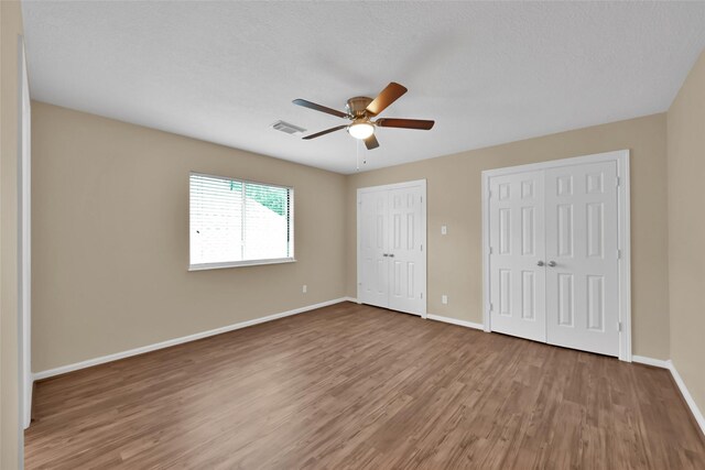 13646 Leafy Arbor Dr, Montgomery, TX 77356 - unfurnished bedroom with multiple closets, wood finished floors, baseboards, and ceiling fan