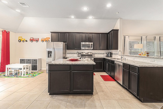 23722 Willow Haven Dr, Spring, TX 77389 - kitchen with stainless steel appliances, a sink, a center island, light stone counters, and vaulted ceiling