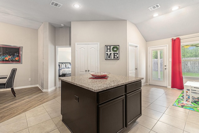 23722 Willow Haven Dr, Spring, TX 77389 - kitchen featuring light tile patterned floors, vaulted ceiling, a center island, light stone counters, and baseboards