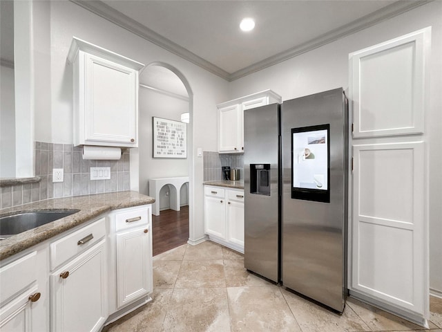 15319 Ochre Leaf Trl, Cypress, TX 77433 - kitchen with stainless steel fridge with ice dispenser, ornamental molding, white cabinetry, tasteful backsplash, and arched walkways