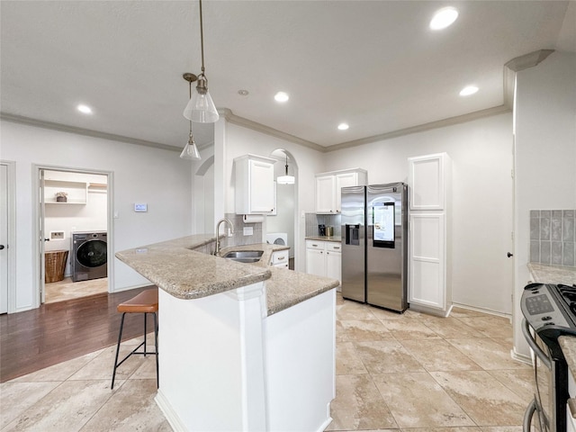 15319 Ochre Leaf Trl, Cypress, TX 77433 - kitchen with appliances with stainless steel finishes, washer / dryer, a sink, a peninsula, and a kitchen bar