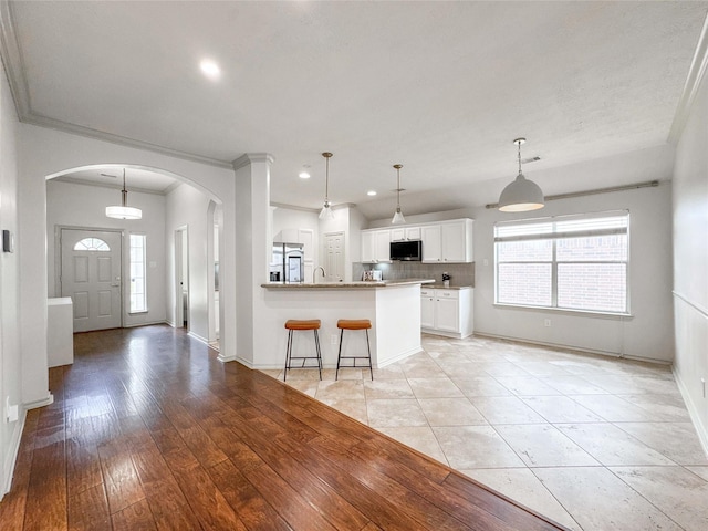 15319 Ochre Leaf Trl, Cypress, TX 77433 - kitchen with stainless steel appliances, arched walkways, white cabinetry, baseboards, and crown molding