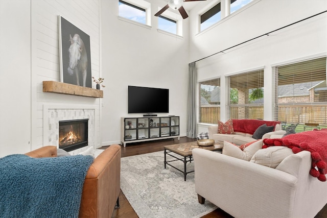 27121 Holtwood Grove Rd, Magnolia, TX 77354 - living area featuring a ceiling fan, a high ceiling, wood finished floors, and a high end fireplace