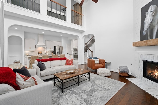 27121 Holtwood Grove Rd, Magnolia, TX 77354 - living area with a fireplace with flush hearth, dark wood-style floors, stairway, a high ceiling, and baseboards