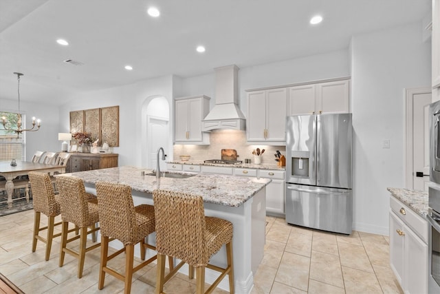 27121 Holtwood Grove Rd, Magnolia, TX 77354 - kitchen featuring appliances with stainless steel finishes, a sink, custom range hood, tasteful backsplash, and a breakfast bar