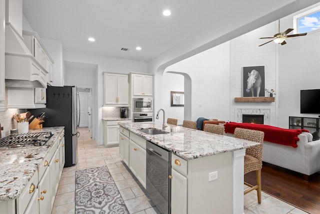 27121 Holtwood Grove Rd, Magnolia, TX 77354 - kitchen featuring stainless steel appliances, a sink, open floor plan, a large fireplace, and ceiling fan