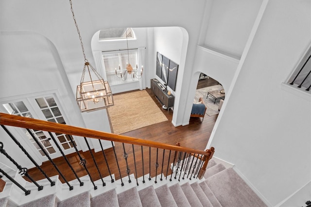27121 Holtwood Grove Rd, Magnolia, TX 77354 - stairway with a chandelier, arched walkways, baseboards, wood finished floors, and a high ceiling