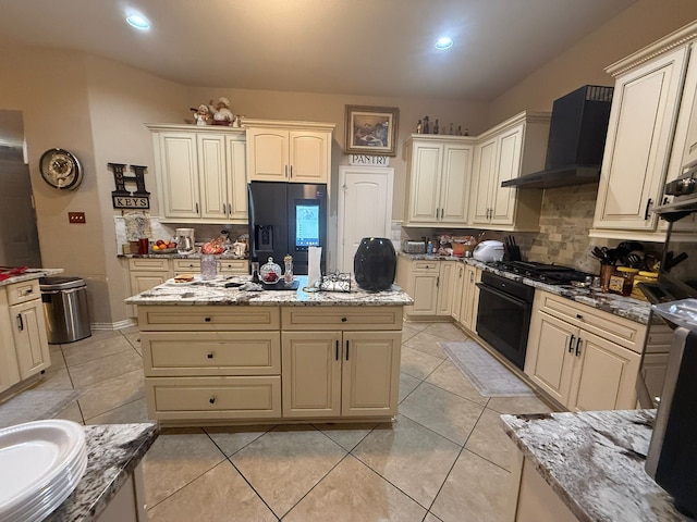 422 Old Orchard Dr, Dickinson, TX 77539 - kitchen with black appliances, wall chimney range hood, decorative backsplash, cream cabinets, and light stone countertops