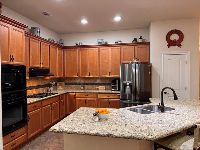 115 Carriage Ct, Magnolia, TX 77354 - kitchen with black appliances, a sink, a kitchen bar, under cabinet range hood, and a center island with sink