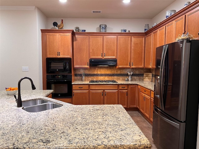 115 Carriage Ct, Magnolia, TX 77354 - kitchen with black appliances, a sink, under cabinet range hood, brown cabinets, and recessed lighting
