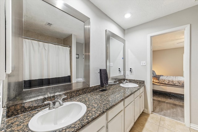 2515 Spring Dusk Ln, Spring, TX 77373 - full bathroom featuring double vanity, connected bathroom, tile patterned flooring, a textured ceiling, and baseboards