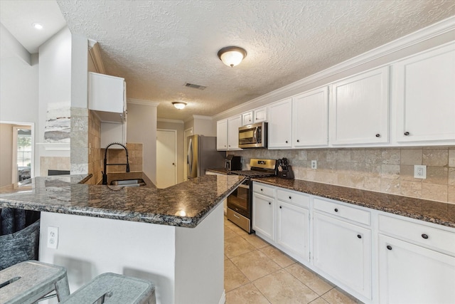 2515 Spring Dusk Ln, Spring, TX 77373 - kitchen featuring stainless steel appliances, a sink, white cabinets, a peninsula, and a textured ceiling