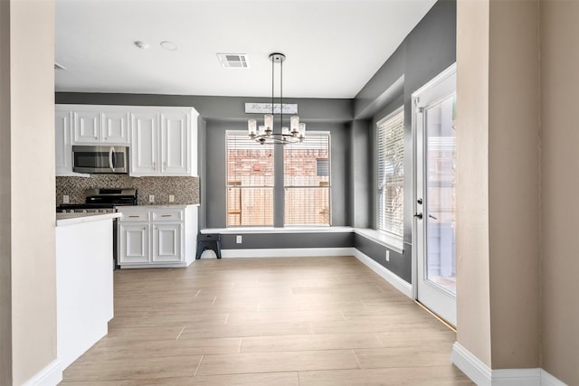 3106 Five Oaks Dr, Missouri City, TX 77459 - kitchen with stainless steel microwave, stove, light wood-style flooring, a chandelier, and white cabinetry