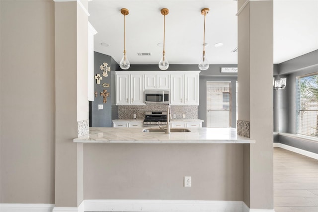3106 Five Oaks Dr, Missouri City, TX 77459 - kitchen featuring appliances with stainless steel finishes, tasteful backsplash, light stone countertops, a peninsula, and pendant lighting