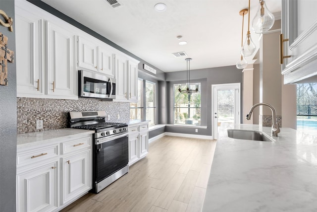 3106 Five Oaks Dr, Missouri City, TX 77459 - kitchen featuring appliances with stainless steel finishes, light stone countertops, white cabinetry, decorative backsplash, and recessed lighting