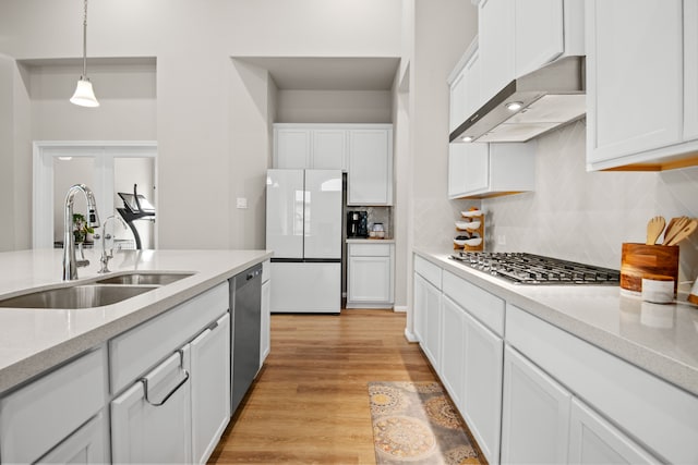 7918 Summit Trail Ln, Porter, TX 77365 - kitchen featuring appliances with stainless steel finishes, a sink, tasteful backsplash, wall chimney range hood, and white cabinetry