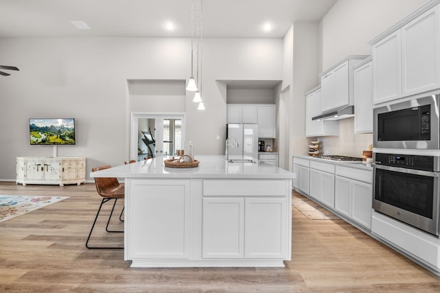 7918 Summit Trail Ln, Porter, TX 77365 - kitchen featuring stainless steel appliances, a sink, white cabinetry, light countertops, and an island with sink