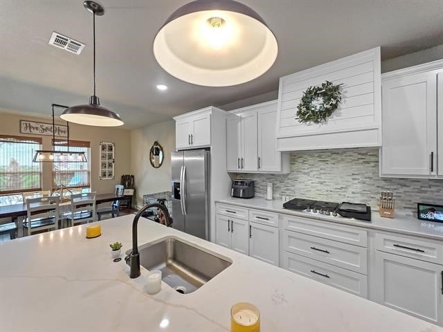 14845 Norma Jane Ln, Beaumont, TX 77713 - kitchen with appliances with stainless steel finishes, a sink, white cabinetry, decorative light fixtures, and decorative backsplash