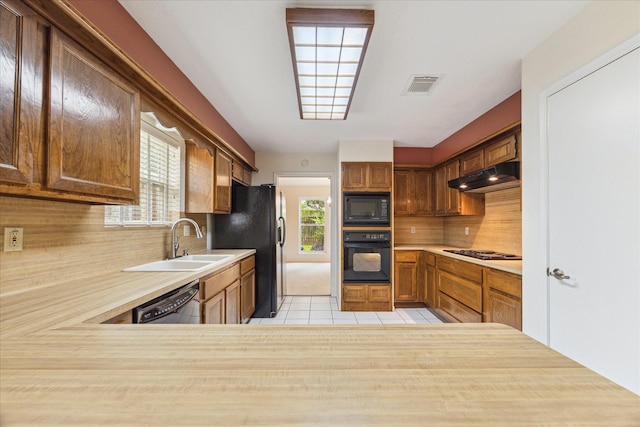 2719 Williams Grant St, Sugar Land, TX 77479 - kitchen featuring black appliances, under cabinet range hood, a sink, light tile patterned flooring, and tasteful backsplash