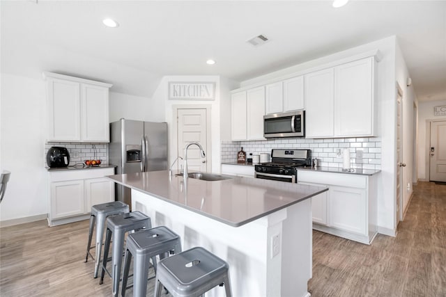 8219 Molasses Way, Rosharon, TX 77583 - kitchen with a sink, stainless steel appliances, a breakfast bar area, an island with sink, and tasteful backsplash
