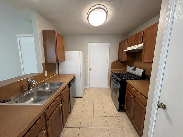 2662 Kiplands Way Dr, Houston, TX 77014 - kitchen with stainless steel appliances, under cabinet range hood, a sink, brown cabinetry, and light tile patterned floors