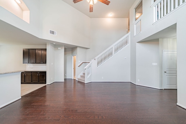 16659 Bluefin St, Crosby, TX 77532 - unfurnished living room with ceiling fan, wood finished floors, a high ceiling, stairs, and baseboards