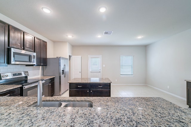 16659 Bluefin St, Crosby, TX 77532 - kitchen with stainless steel appliances, light tile patterned flooring, light stone countertops, decorative backsplash, and dark brown cabinetry