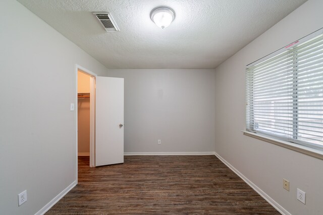 19914 Big Timber Dr, Humble, TX 77346 - unfurnished bedroom featuring a textured ceiling, dark wood-style flooring, a walk in closet, and a closet