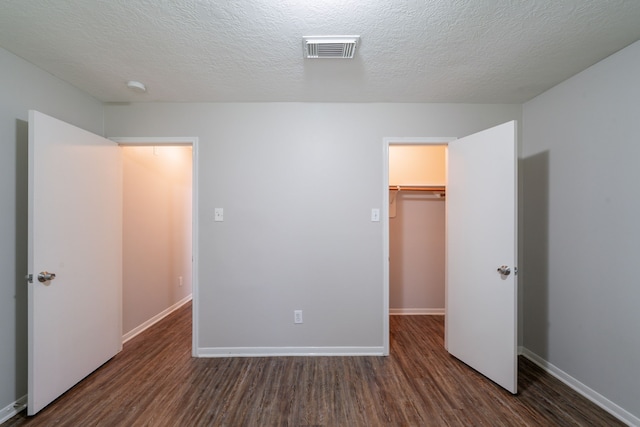 19914 Big Timber Dr, Humble, TX 77346 - unfurnished bedroom with wood finished floors, a closet, a walk in closet, and a textured ceiling
