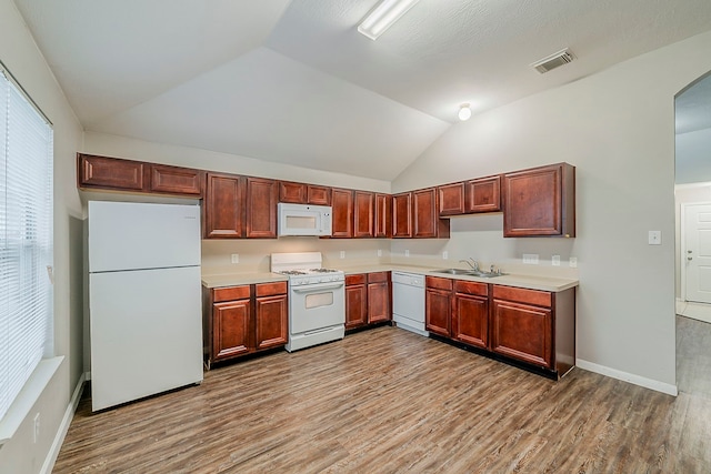 2511 Muscory Dr, Humble, TX 77396 - kitchen featuring white appliances, light wood-type flooring, vaulted ceiling, light countertops, and a sink