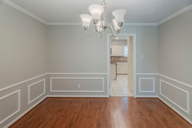 5206 Graystone Ln, Houston, TX 77069 - unfurnished dining area with wood finished floors, a chandelier, ornamental molding, a decorative wall, and a wainscoted wall