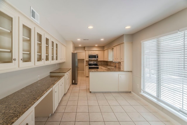 5206 Graystone Ln, Houston, TX 77069 - kitchen featuring appliances with stainless steel finishes, a sink, light tile patterned floors, stone countertops, and glass insert cabinets