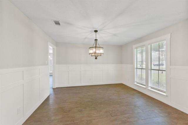 704 Balmoral Ct, Friendswood, TX 77546 - empty room with a wainscoted wall, a chandelier, a decorative wall, and wood finished floors
