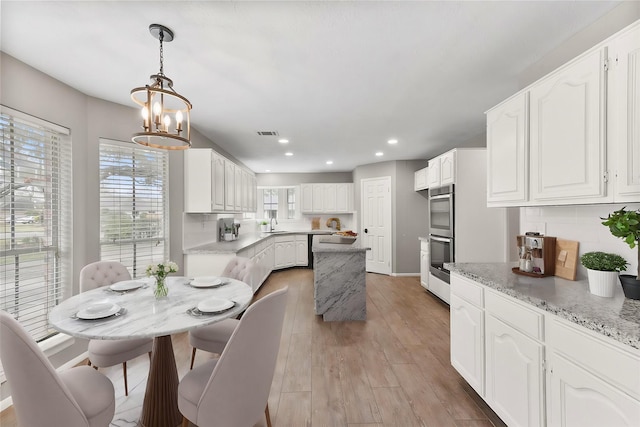 704 Balmoral Ct, Friendswood, TX 77546 - dining area with a chandelier, recessed lighting, healthy amount of natural light, light wood-type flooring, and baseboards