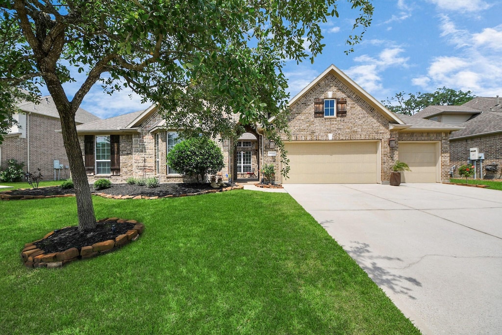 22714 Wilbur Ln, Tomball, TX 77375 - view of front facade with an attached garage, concrete driveway, a front lawn, and brick siding