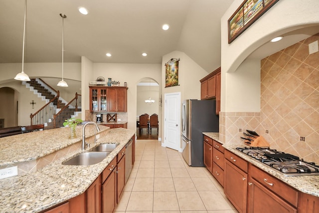 22714 Wilbur Ln, Tomball, TX 77375 - kitchen featuring a sink, stainless steel appliances, arched walkways, backsplash, and light stone counters