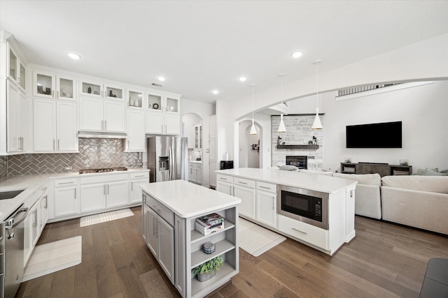 1120 Wakefield Dr, Houston, TX 77018 - kitchen featuring stainless steel appliances, a kitchen island, arched walkways, open floor plan, and decorative backsplash