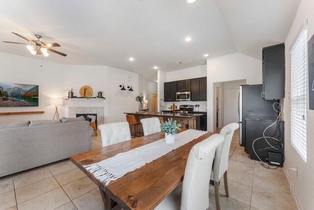 9998 Chimney Swift Ln, Conroe, TX 77385 - dining room featuring light tile patterned floors, ceiling fan, lofted ceiling, a tiled fireplace, and recessed lighting