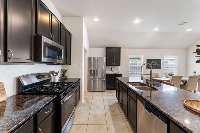 9998 Chimney Swift Ln, Conroe, TX 77385 - kitchen featuring appliances with stainless steel finishes, a sink, tasteful backsplash, dark stone countertops, and light tile patterned floors