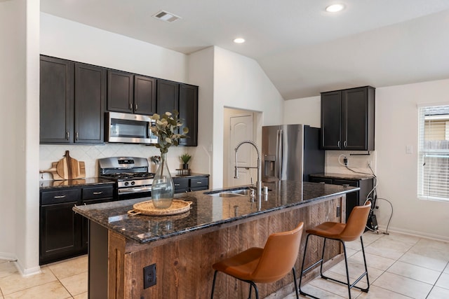 9998 Chimney Swift Ln, Conroe, TX 77385 - kitchen featuring appliances with stainless steel finishes, a sink, dark stone counters, backsplash, and vaulted ceiling