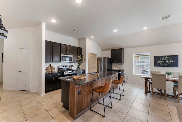 9998 Chimney Swift Ln, Conroe, TX 77385 - kitchen with appliances with stainless steel finishes, a sink, a kitchen bar, dark stone countertops, and light tile patterned flooring