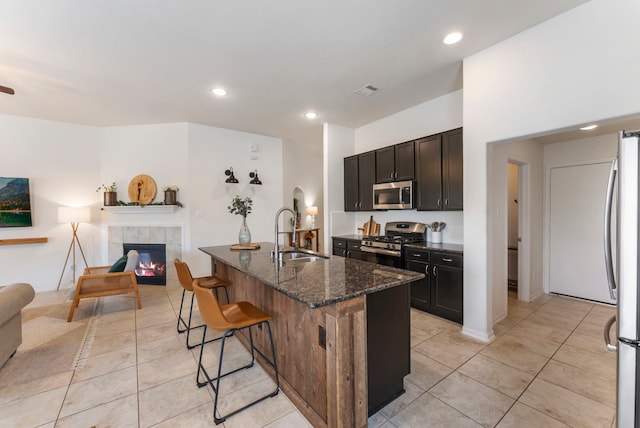 9998 Chimney Swift Ln, Conroe, TX 77385 - kitchen with stainless steel appliances, a sink, open floor plan, a kitchen bar, and dark stone countertops