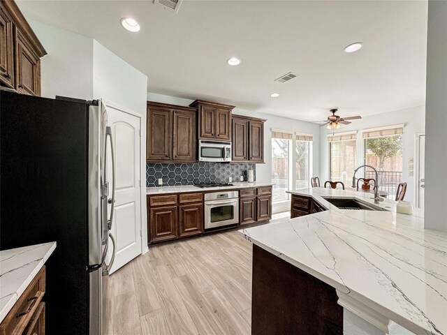 6081 Trent Ct, League City, TX 77573 - kitchen with appliances with stainless steel finishes, a sink, tasteful backsplash, light stone counters, and a ceiling fan