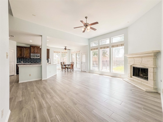 6081 Trent Ct, League City, TX 77573 - living area featuring a ceiling fan, light wood-type flooring, a premium fireplace, and baseboards