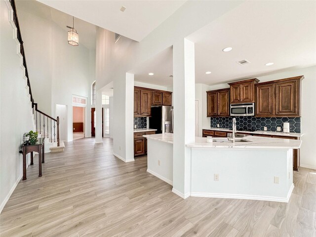 6081 Trent Ct, League City, TX 77573 - kitchen with appliances with stainless steel finishes, backsplash, light wood-style flooring, a large island with sink, and recessed lighting